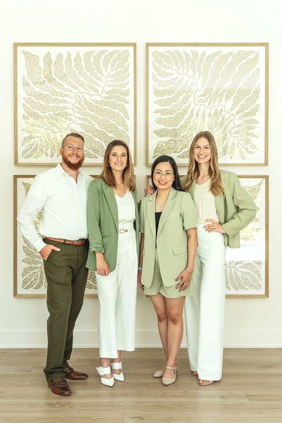 Members of Wisdom House Realty Group standing together in front of leaf wall art